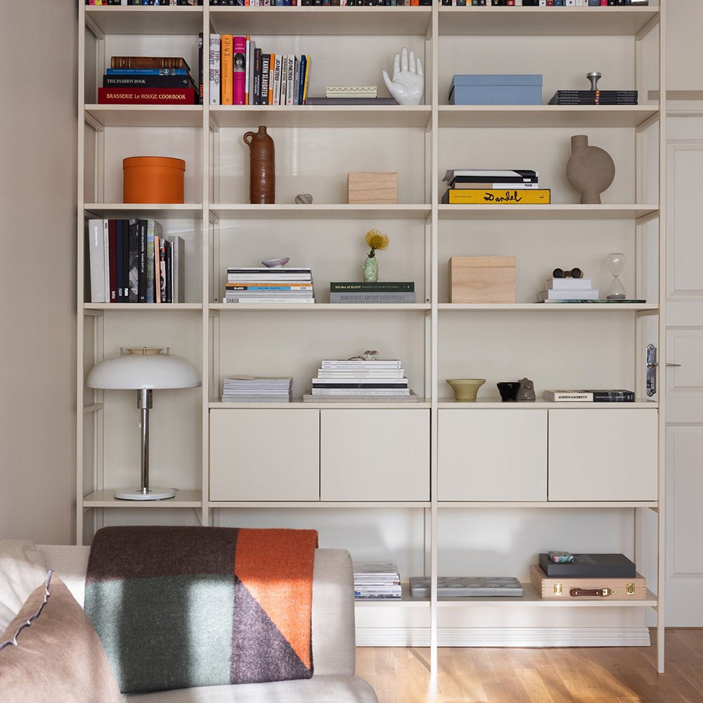 bokhylla i off white med böcker, lampa och förvaring